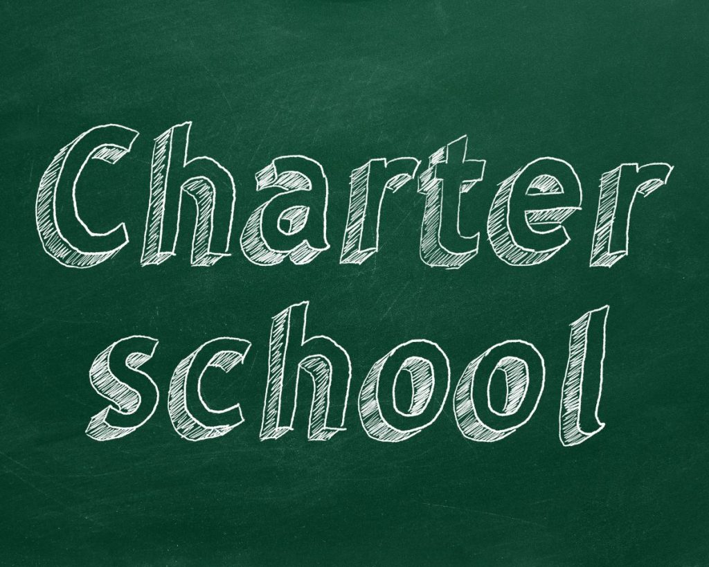 The words charter school written in white chalk on a green blackboard