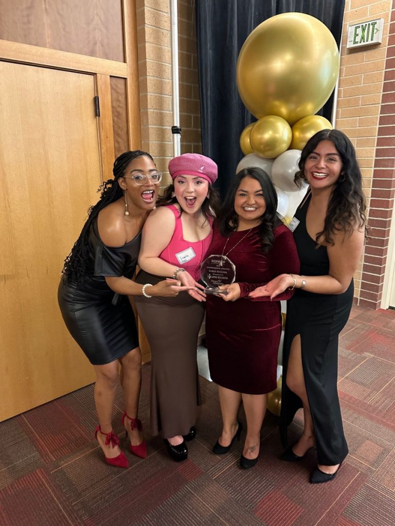 Photo of four women with a gold balloon and an award plaque